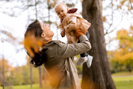 Photo for Young woman holding a cute baby girl in the autumn park - Royalty Free Image