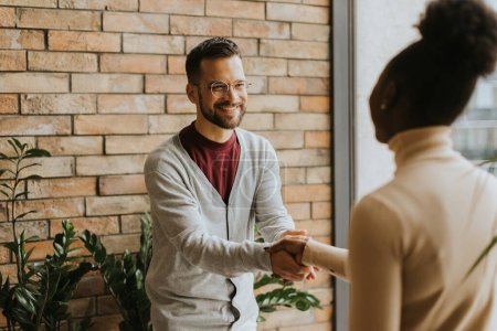 Photo for Handsome young multiethnic business couple handshaking in the modern office - Royalty Free Image