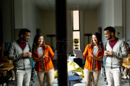 Foto de Joven pareja de negocios de pie con tableta digital frente a su equipo en la oficina moderna - Imagen libre de derechos