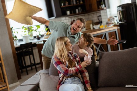 Photo for Cheerful trio engages in a spirited pillow fight, laughter filling their warm, inviting home - Royalty Free Image