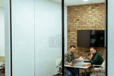 Téléchargez les photos : Deux professionnels s'engagent dans une conversation tout en s'asseyant confortablement dans un salon de bureau, entouré de verdure et d'éléments de design contemporain - en image libre de droit