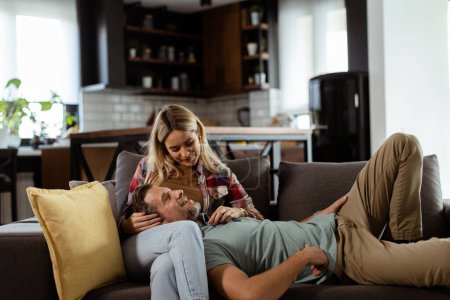 Photo for Couple shares a tender and peaceful moment as one rests their head on the others lap, surrounded by the warmth and comfort of their living room. - Royalty Free Image