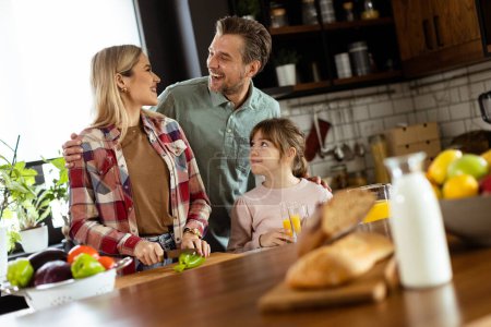 Foto de La familia comparte una sonrisa mientras preparan el desayuno juntos en una acogedora cocina bien iluminada - Imagen libre de derechos