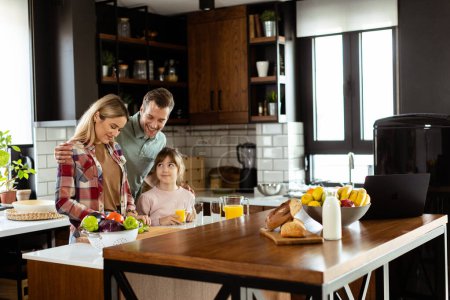 Photo for Family shares a smile while preparing breakfast together in a cozy, well-lit kitchen setting - Royalty Free Image