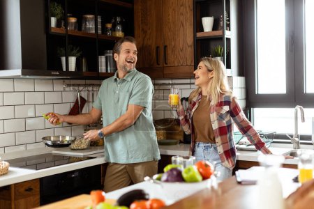 Téléchargez les photos : Un homme et une femme qui rient dans une cuisine confortable et bien organisée - en image libre de droit