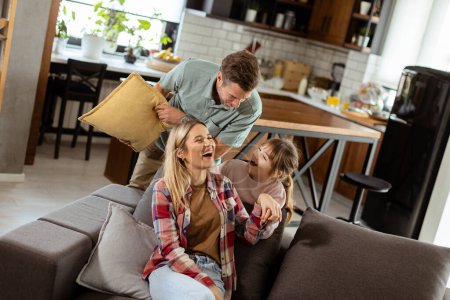 Photo for Cheerful trio engages in a spirited pillow fight, laughter filling their warm, inviting home - Royalty Free Image