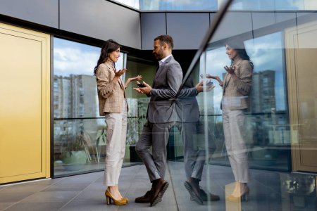 Photo for Two business professionals shake hands outside a contemporary building, their interaction mirrored in the glass. - Royalty Free Image