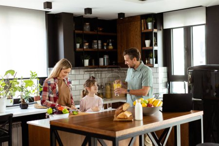 Young family chatting and preparing food around a bustling kitchen counter filled with fresh ingredients and cooking utensils