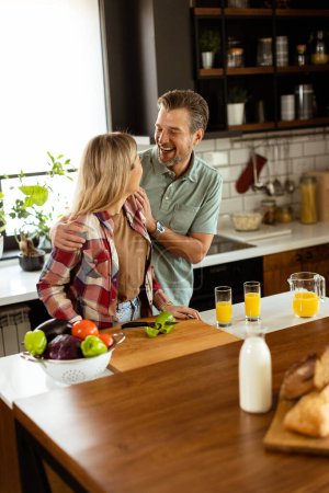 Téléchargez les photos : Un couple heureux profite d'une conversation décontractée avec des boissons du matin dans leur cuisine ensoleillée. - en image libre de droit