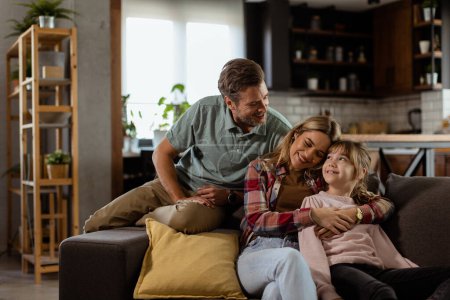 Photo for Joyful family shares a relaxed, affectionate moment on the sofa, illuminated by soft natural light - Royalty Free Image