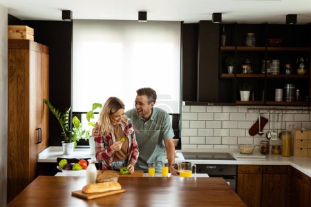Téléchargez les photos : Un couple heureux profite d'une conversation décontractée avec des boissons du matin dans leur cuisine ensoleillée. - en image libre de droit