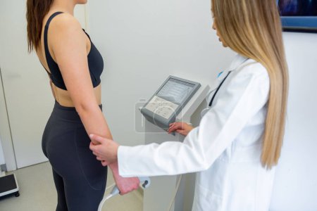 Photo for A health practitioner assists a woman with a body composition test using advanced equipment. - Royalty Free Image