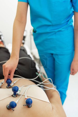 A patient relaxes while a medical professional carefully administers an ECG test.