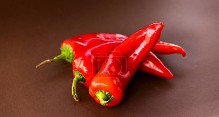Foto de Bunch of red bell peppers close up on brown background - Imagen libre de derechos