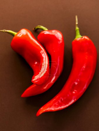 Foto de Bunch of red bell peppers close up on brown background - Imagen libre de derechos