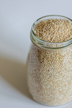 Téléchargez les photos : Quinoa dans un bocal en verre près sur fond blanc - en image libre de droit