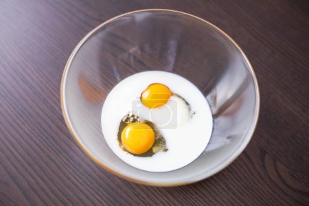 Téléchargez les photos : Gros plan sur les œufs et le lait prêts à être mélangés dans un bol en verre - en image libre de droit