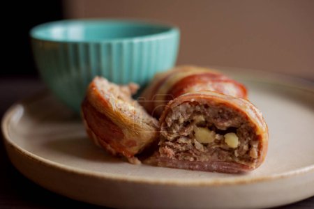 Photo for Savory delight: delicious dish with meatballs wrapped in bacon, filled with mozzarella and yogurt sauce - Royalty Free Image