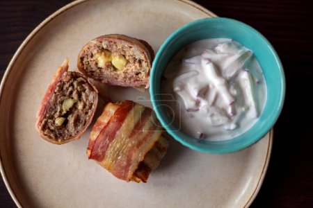 Delicia sabrosa: delicioso plato con albóndigas envueltas en tocino, llenas de mozzarella y salsa de yogur