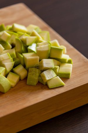 chopped zucchini into cubes on wooden board close-up