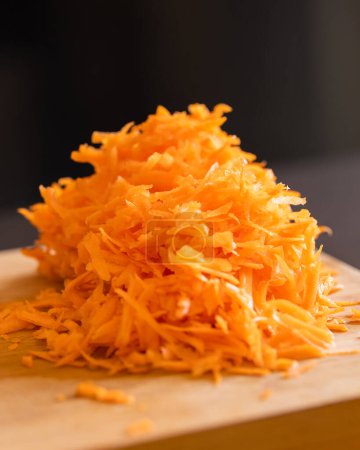 grated fresh carrots on wooden board close-up