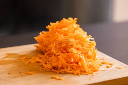 grated fresh carrots on wooden board close-up