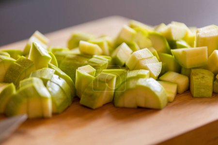 chopped zucchini into cubes on wooden board close-up