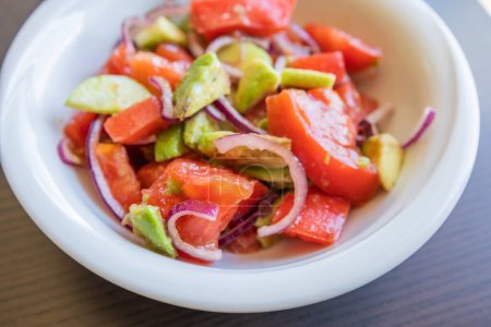 Köstlicher Sommersalat mit Tomaten, Gurken, roten Zwiebeln und Avocado aus nächster Nähe