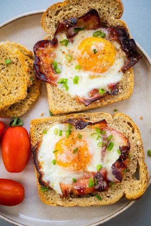  Baked Bacon and Eggs in Bread on White Plate with Fresh Green Onion Close-Up