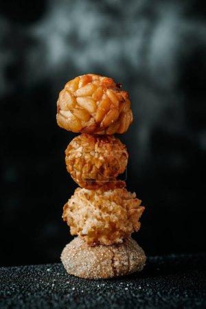 Photo for Stack of panellets, a confection typical of All Saints Day in Catalonia, Spain, in different varieties: with pine nut bits, with almond bits, a coconut panellet and a vanilla panellet at the base - Royalty Free Image