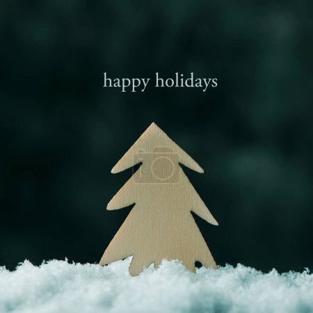 Téléchargez les photos : Gros plan d'un sapin découpé sur bois sur la neige et le texte joyeuses fêtes - en image libre de droit