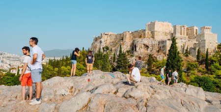 Foto de Atenas, Grecia - 29 de agosto de 2022: Personas en la cima de una colina en busca del mejor lugar para tomar fotos frente a la Acrópolis de Atenas, en Grecia, en un día de verano - Imagen libre de derechos
