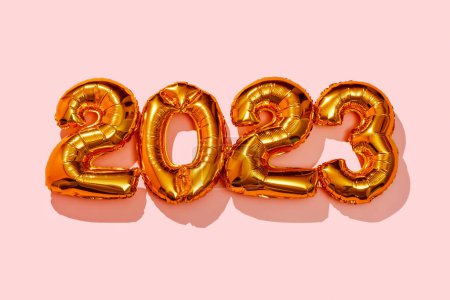 Foto de Algunos globos dorados en forma de número que forman el número 2023, como el nuevo año, sobre un fondo rosa - Imagen libre de derechos