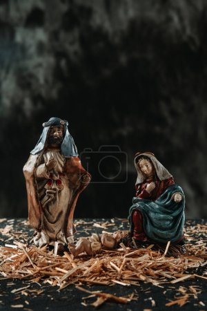 Photo for Closeup of a depiction of the holy family, of saint joseph, the virgin mary and the child jesus, on the straw, against a dark background - Royalty Free Image