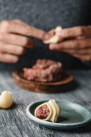 Téléchargez les photos : Un homme remplit les galettes de pâtes avec de la viande hachée, pour préparer sopa de galets ou escudella de Nadal, typiquement mangé à Noël en Catalogne, Espagne - en image libre de droit