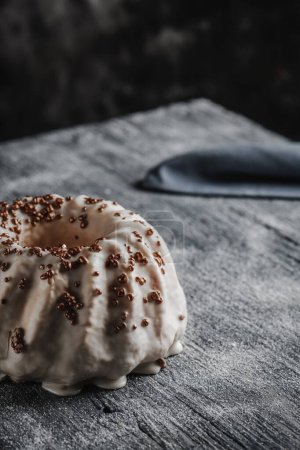 Téléchargez les photos : Gros plan d'un gâteau gugelhupf, recouvert d'un délicieux glaçage à la vanille, placé sur une table en bois rustique gris - en image libre de droit