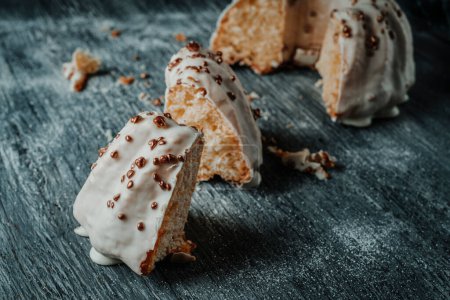 Foto de Primer plano de algunos pedazos de un delicioso pastel de gugelhupf cubierto con un glaseado de vainilla en una mesa de madera rústica gris - Imagen libre de derechos
