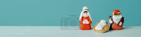 Photo for The holy family, formed by the virgin mary, the child jesus, and saint joseph, on a white surface, against a blue background, in a panoramic format to use as web banner - Royalty Free Image
