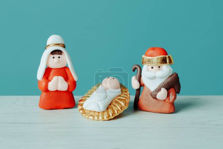 Photo for Closeup of a childish depiction of the holy family, formed by the child jesus, the virgin mary and saint joseph, on a white surface, against a blue background - Royalty Free Image