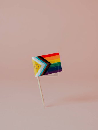 Téléchargez les photos : Un drapeau de fierté de progrès intersexe inclusif attaché à un poteau en bois placé sur un fond brun pâle, avec un espace vide sur le dessus - en image libre de droit
