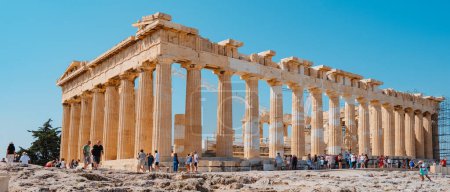 Foto de Atenas, Grecia - 30 de agosto de 2022: Muchos visitantes observan de cerca los restos del famoso Partenón, en la Acrópolis de Atenas, Grecia, en un formato panorámico - Imagen libre de derechos