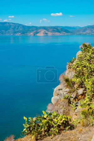 Foto de A view of the Aegean sea, since the top of a hill in Napflio, Greece, with some prickly pear cactuses, on a summer day - Imagen libre de derechos