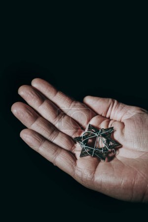 Photo for The hand of a man with a star of david tied with some barbed wire, against a black background - Royalty Free Image