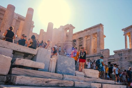 Téléchargez les photos : Athens, Greece - August 30, 2022: A crowd of visitors walk by the Propylaia of the Acropolis of Athens, in Greece, the ancient gateway to the site, on a summer day - en image libre de droit