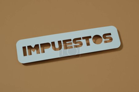 Téléchargez les photos : Les taxes sur les textes écrits en espagnol sur fond marron avec un panneau bleu pâle - en image libre de droit
