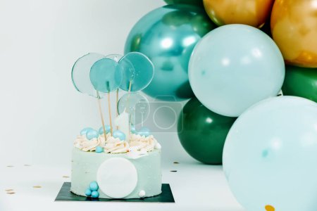 Téléchargez les photos : A blue cake and some balloons of different colors and sizes forming an elegant arrangement as a decoration for a birthday party a wedding or a baby cake smash - en image libre de droit