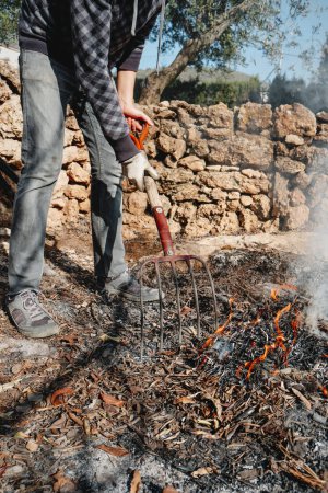 Téléchargez les photos : Un homme brûle des branches, des feuilles et d'autres restes de plantes après la taille de différents arbres, dans un verger en Catalogne, Espagne - en image libre de droit