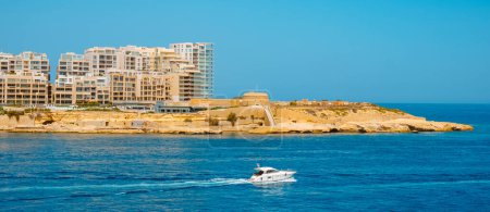 Foto de A panoramic view of Tigne Point in Sliema, Malta, and Fort Tigne on the right, next to some modern apartment towers, on a sunny summer day, as is seen from the sea - Imagen libre de derechos