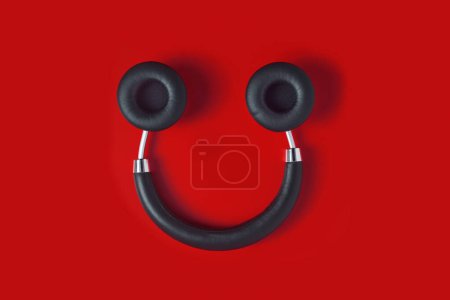 Photo for A pair of upside down black wireless full size headphones, resembling a smiley face, on a red background - Royalty Free Image
