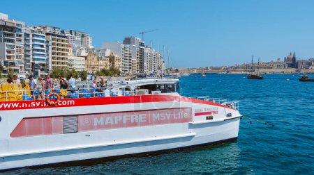 Foto de Sliema, Malta - 5 de septiembre de 2022: Acaba de llegar un ferry al puerto de Sliema, en Malta, y el casco antiguo de La Valeta a la derecha en el fondo - Imagen libre de derechos